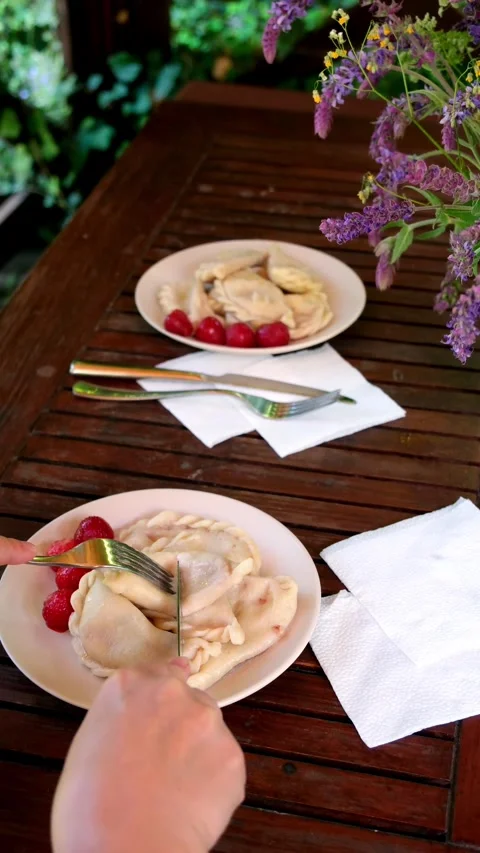 Close up hands cutting boiled dumplings on wooden patio table, white plate, red Stock Footage 345161975