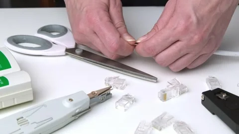 Close-up of hands cutting Ethernet cable wires on white desk with networkin.. Stock Footage 309822844