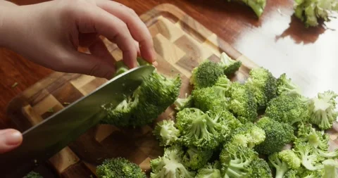 Close-up of hands cutting fresh broccoli on wooden board in kitchen healthy Stock-Footage 319343121