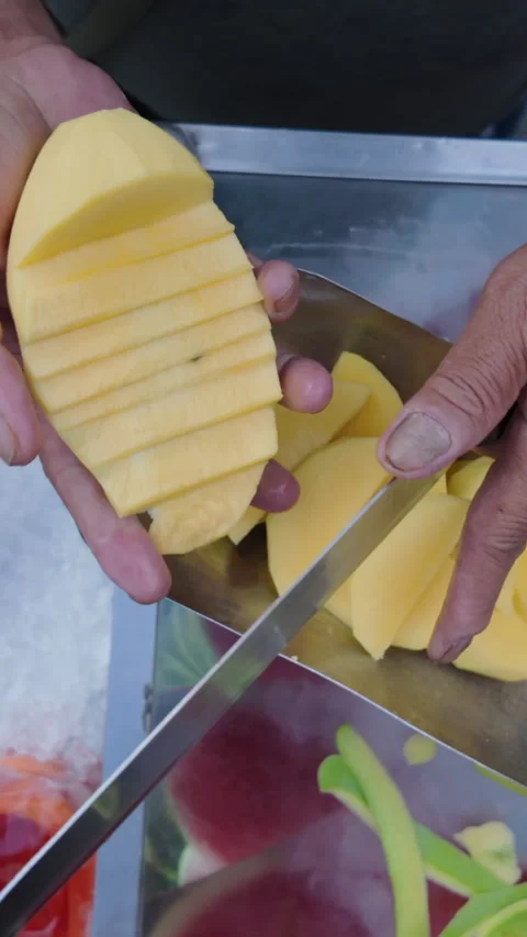 Close-up of hands cutting fresh fruit with a big knife on a cart on the street Stock Footage 276984168