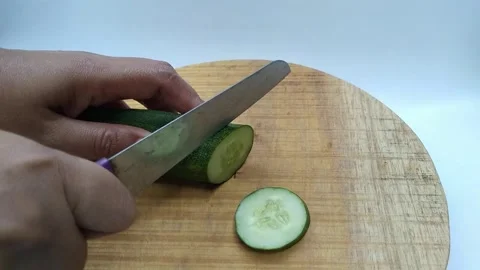 Close-up of hands cutting fresh green cucumber with a knife on a wooden cut.. Stock Footage 340598219