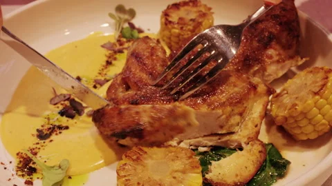 Close up of hands cutting a grilled chicken dish with fork and knife Stock Footage 332679813