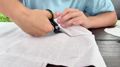 Close-Up of Hands Cutting Light Fabric With Scissors on Wooden Table Video stock 346499466