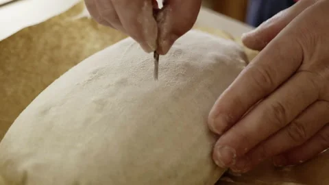 Close up hands cutting a pattern on the sourdough bread loaf Stock Footage 142360281