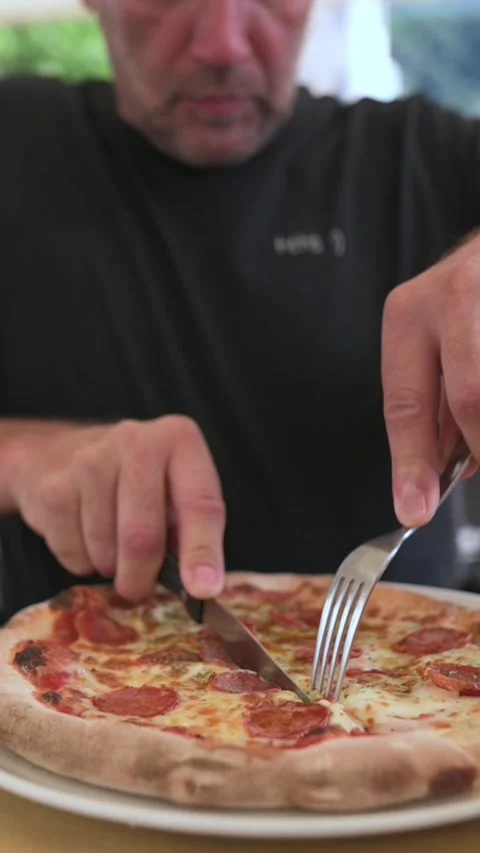 Close-up of hands cutting pepperoni pizza at restaurant table Видео 318579246
