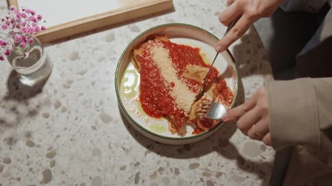Close up of hands cutting into plate of red sauce lasagna with grated cheese on Stock Footage 345071636