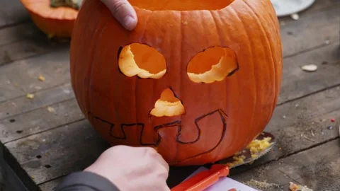 Close-Up of Hands Cutting a Pumpkin Face for a Halloween Jack o Lantern Stock Footage 319470419