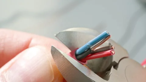 Close-up of hands cutting red-brown cable with pliers for motion sensor. Stock Footage 303384987