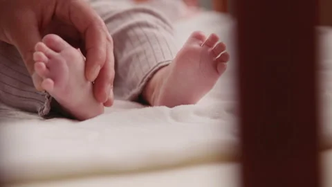 Close up hands dad gently touching and stroking her newborn baby legs. Loving Stock Footage 207107086