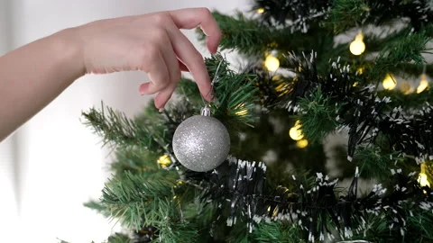 Close-up hands decorating Christmas tree with balls with bright festive lights. Stock Footage 167046660