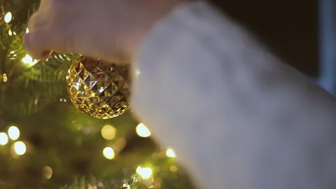 Close up hands decorating Christmas Tree with gold ball and flashlights Stock Footage 258664520