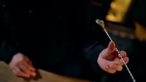 Close-up of hands delicately holding a fine metal chain above a worn wooden Vídeos de archivo 318655508