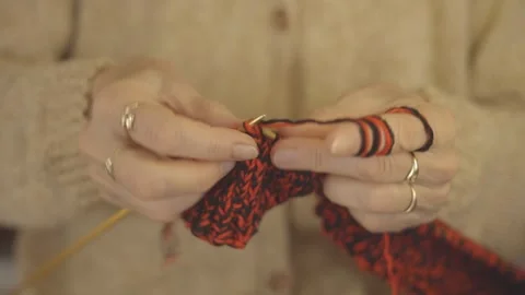 A close-up of hands delicately knitting with white yarn during a cozy afternoon Video stock 283835726