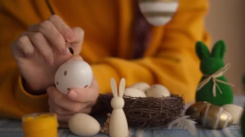 A close-up of hands delicately painting an Easter egg with golden details. .. Stock Footage 304087602