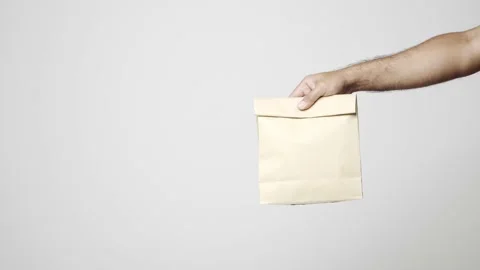 Close up hands delivery man sending the food paper bag on isolated white backgro Stock Footage 144257790