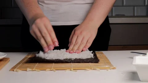 Close up of hands distributing white rice across nori seaweed sheet on bamb.. Stock Footage 320954626