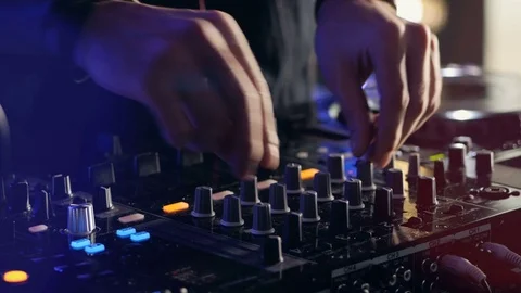 Close-up. Hands of DJ tweak various track controls on DJ mixer console at Stock Footage 74604464