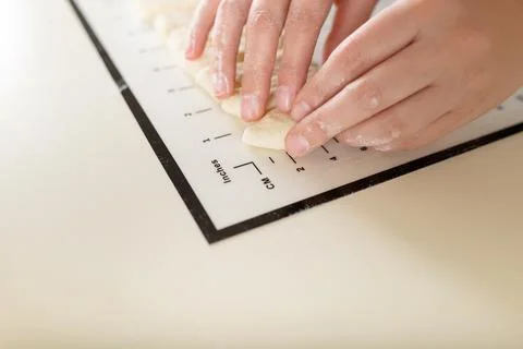 Close-up of hands doing cooking on a kitchen mat with markings. Copy space and Stock Photos
