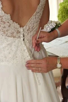 Close up of Hands Doing Final Buttoning of Bride's Wedding Dress Stock Photos