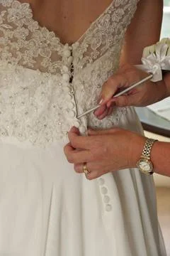 Close up of Hands Doing Final Buttoning of Bride's Wedding Dress Stock Photos