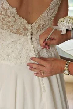 Close up of Hands Doing Final Buttoning of Bride's Wedding Dress Stock Photos