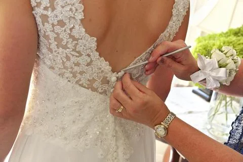 Close up of Hands Doing Final Buttoning of Bride's Wedding Dress Stock Photos