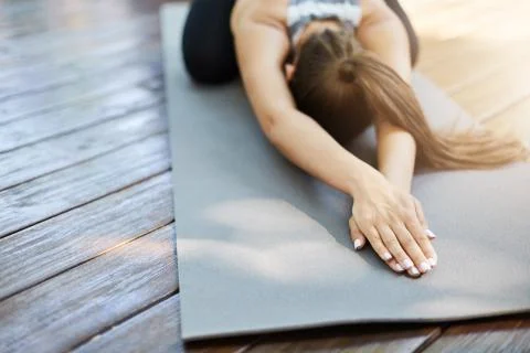 Close up of hands doing yoga or pilates laying on a grey mat in a temple or a Stock Photos