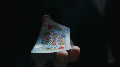Close-up of the hands of a dressed magician performing a card trick. Cards fly Stock Footage 129359603