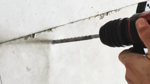 Close-Up of Hands Drilling a Hole in Concrete Wall with a Red Rotary Hammer Stock Footage 301479148