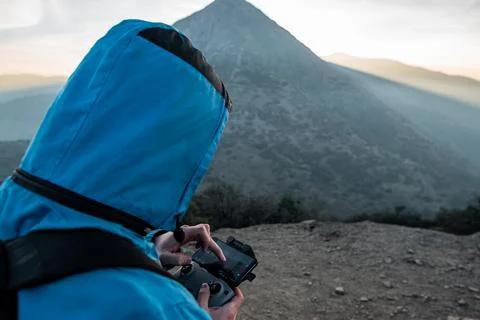 Close-up hands-on drone control in nature with sunset in the background Stock Photos