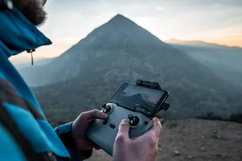 Close-up hands-on drone control in nature with sunset in the background Stock Photos