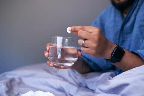 A close up of hands dropping an effervescent tablet into water Stock Photos