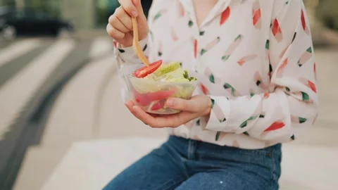 Close up of hands eating healthy vegetable salad with a wooden fork outdoors. Stock Footage 340587609