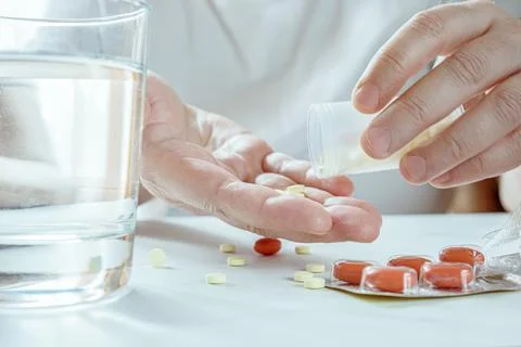 Close-up of hands of elderly man pouring pills into palm. Health problems in  Stock Photos