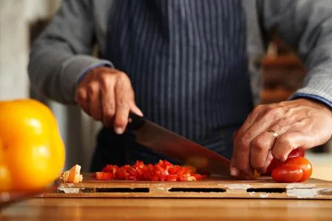 Close up of hands, elderly multi-cultural male chopping up vegetables for Stock Photos