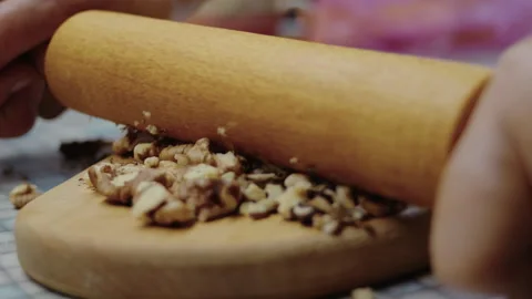 Close-up, hands of an elderly woman crushing nuts with a rolling pin on the Video stock 337119974