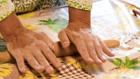 Close-up of hands engaged in rolling out dough with a wooden rolling pin on.. Stock Footage 328830751