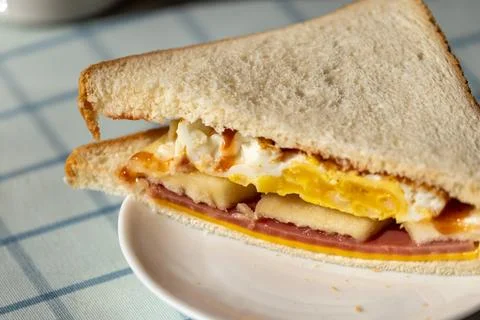 Close-up of hands enjoying a sandwich, a backlit breakfast scene, a documen.. Фото
