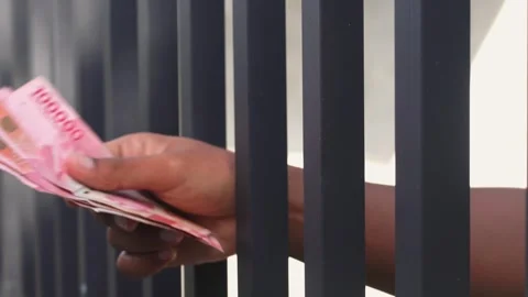 Close-up of hands exchanging Indonesian rupiah through prison bars Stock Footage 335335863