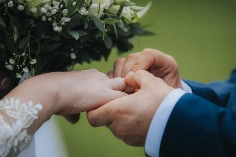 Close-up of hands exchanging wedding rings during a ceremony, adorned with .. Foto stock