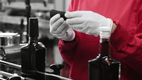 Close-up of the hands of a factory worker putting plastic caps on bottles. Video stock 288411359