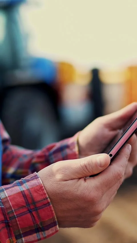 Close-up of hands. Farmer, in red plaid shirt, is typing in tablet smth, against Stock Footage 315094175