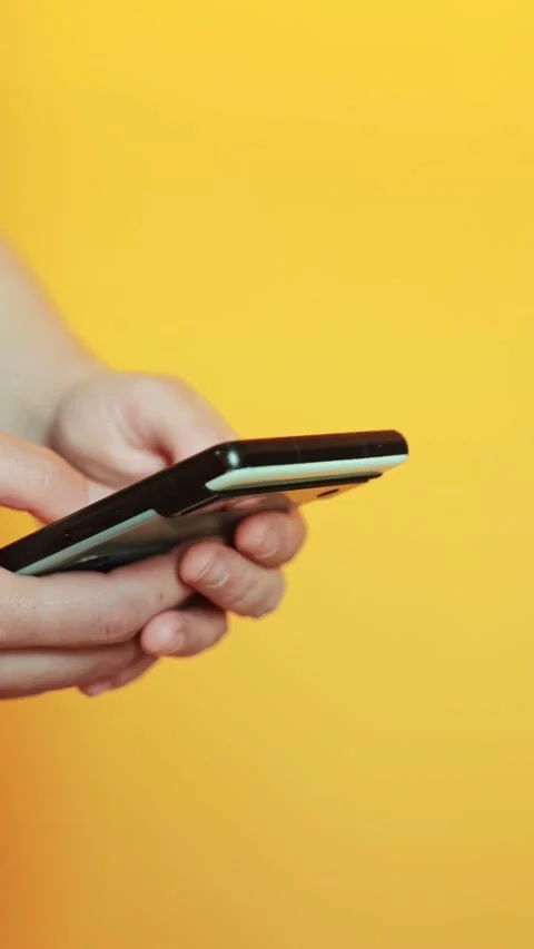 Close up of hands fast typing and texting on smartphone against bright yell.. Stock Footage 338439372