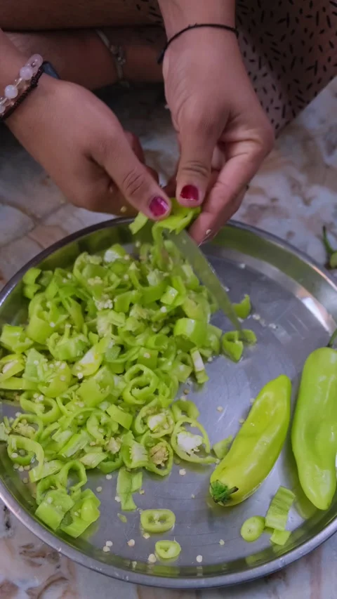 Close up of hands finely chopping fresh light green chillies on a metal plate 動画素材 333203413