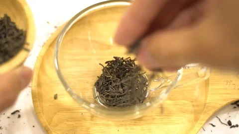 Close up hands fingers put tea leaves to cup glass Stock Footage 110897535