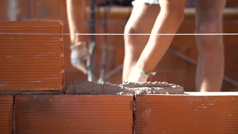 Close up of hands fitting a brick into the wall in front. Use cement to joi.. Video stock 242005196