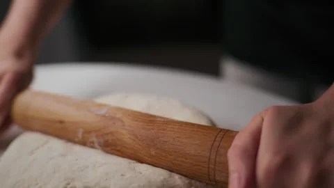 Close-up of hands flattening dough on white surface Видео 336095774