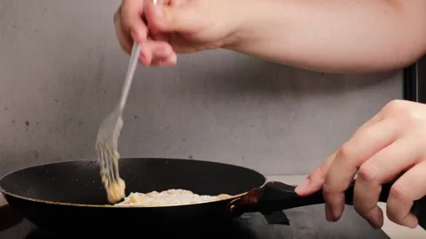 Close-up of hands flipping breaded pork cutlets in a frying pan with a fork.. Stock Footage 320955041