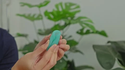 Close-up of hands folding green menstrual cup using the punch-down technique Vidéo 340576367