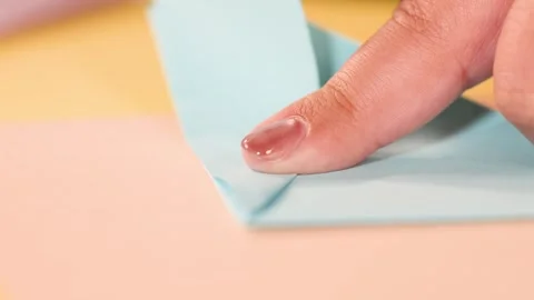 Close Up of Hands Folding Light Blue Origami Paper on Table Stock Footage 327626383